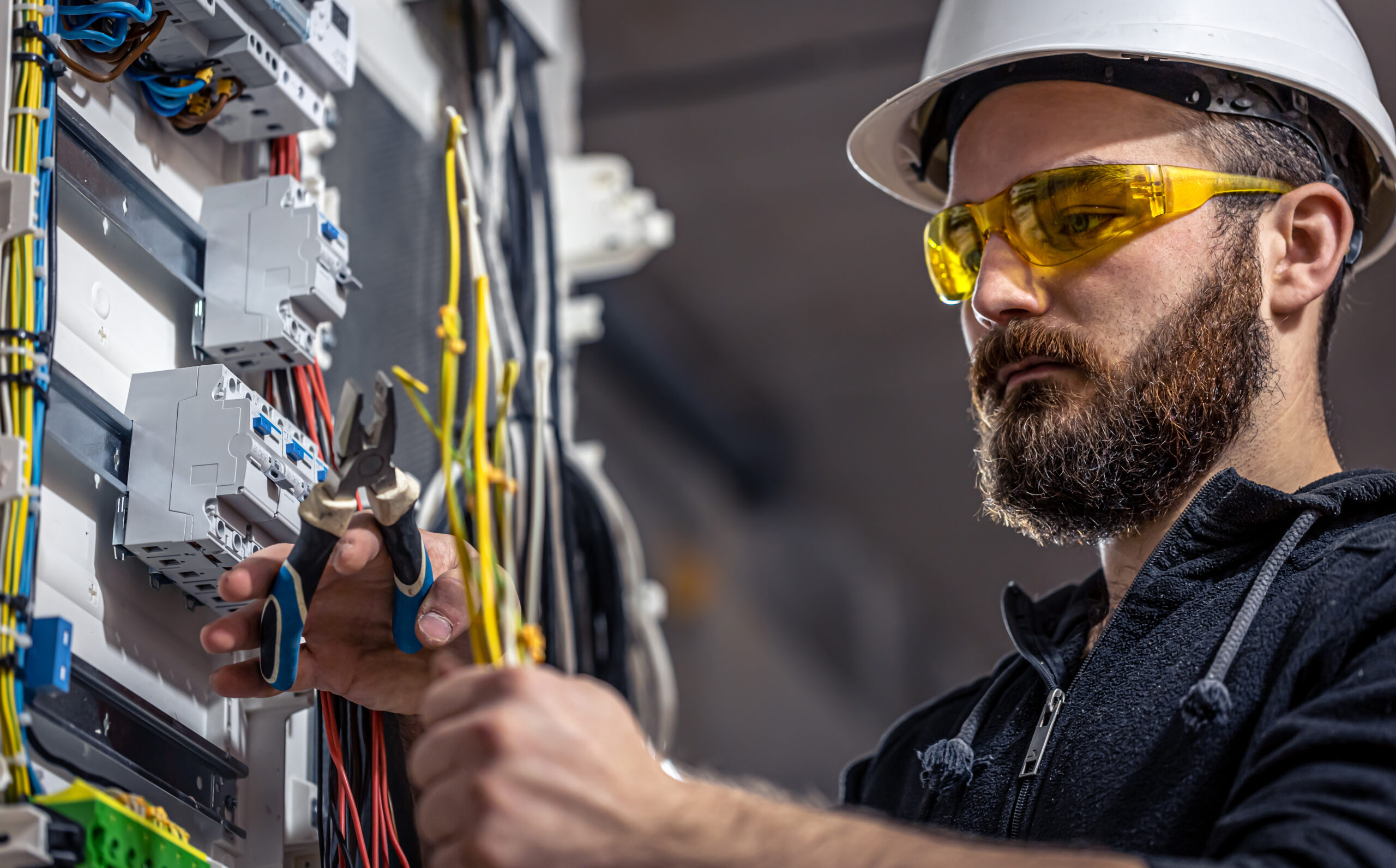 Male electrician at the checkout counter on a blurred background of a switchboard.
